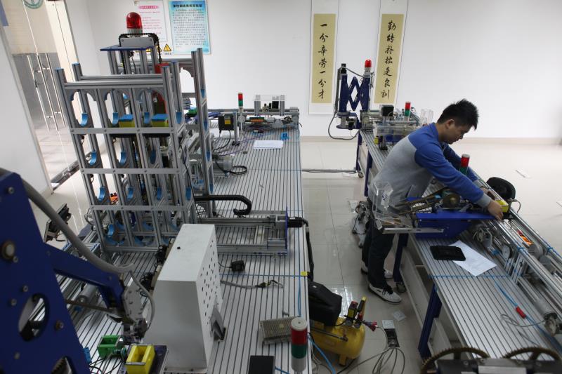 学校与龙头企业合作，引入华为、中兴等企业的知识体系，在校内设立建制班级或开设相关课程。图为学生在先进自动化技术联合示范实验中心学习。